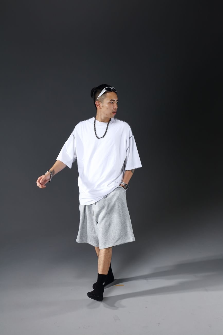 Portrait of a stylish man in oversized streetwear with an edgy pose in a studio setting.